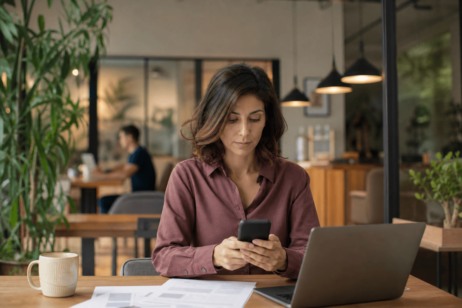 Woman working at a desk in a coworking space checking her phone
